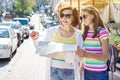 Mom and daughter teenager tourist looking at the map on the street of european city