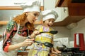 Mom and daughter in white chef hats cook in the kitchen.