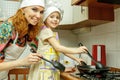 Mom and daughter in white chef hats cook in the kitchen.