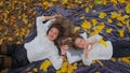 Mom and daughter lay on the ground in the autumn forest