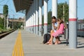 Mom and daughters are waiting for the train on the empty platform of the railway station