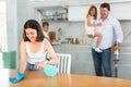 Mom is dusting the table. Father with children vacuuming room