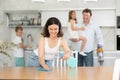 Mom is dusting the table. Father with children vacuuming room