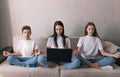 Mom enthusiastically works on the computer the children meditate sitting next to each other on the couch. the concept of work and