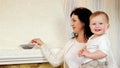 Mom feeding her son with tasty puree with spoon near fireplace, child eating porridge with delight