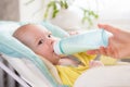 Mother feeds the baby. The toddler drinks milk from a bottle