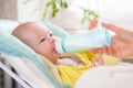 Mother feeds the baby. The toddler drinks milk from a bottle