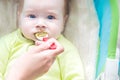 Mom feeds her baby with a spoon close-up of broccoli puree. The child is sad. Soiled face. Face food Royalty Free Stock Photo