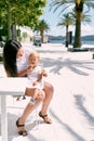 Mom feeds ice cream to a little girl sitting on her lap in a cafe Royalty Free Stock Photo