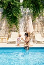 Mom feeds little girl watermelon by the pool