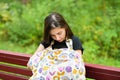 Mom feeds the newborn on the bench. covered with a diaper from prying eyes. Young woman, new mother breastfeeding and caring her