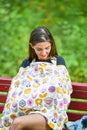 Mom feeds the newborn on the bench. covered with a diaper from prying eyes. Young woman, new mother breastfeeding and caring her Royalty Free Stock Photo