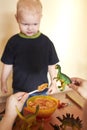 Mom feeds toy dinosaurs from a spoon Royalty Free Stock Photo