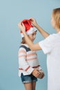 Mom fixing christmas hat for a little girl holding a present box in her hands Royalty Free Stock Photo