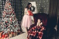 Mom gives a surprise gift to her daughter before the New Year tree. The daughter covered her eyes with her hands Royalty Free Stock Photo