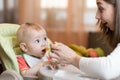 Mom giving homogenized food to her baby son on high chair. Royalty Free Stock Photo