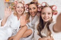 Mom, grandmother and girl in curlers do selfie on the phone.