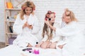 Mom, grandmother and girl in curlers make each other make-up.