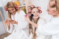 Mom, grandmother and girl in curlers make each other make-up.