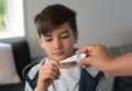 A mom handing a digital Thermometer to a boy