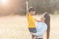 Mom is happily carrying her son in the meadow. Asian young mother and her little child at sunset. Soft focus Royalty Free Stock Photo