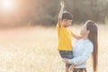 Mom is happily carrying her son in the meadow. Asian young mother and her little child at sunset. Soft focus Royalty Free Stock Photo