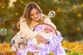 Mom happily looks at the two-month-old baby sleeping in a basket, flying soap bubbles Royalty Free Stock Photo