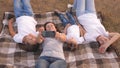 Mom and happy children are photographed on smartphone in park. Mother and daughters take a selfie while traveling, lying