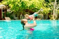 Mom with a happy small child of eight months having fun and swimming in the pool. Young woman kissing her baby