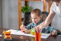 Mom is helping child to draw with pencils on paper in an album. Preschool education and development of creativity Royalty Free Stock Photo