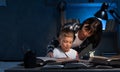 Mom helping little son to do homework at night. student boy doing his school homework with his mother, at home, he is Royalty Free Stock Photo