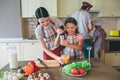 Mom helps her daughter to blend eggs. Girl is using blender. Woman holds cup where eggs are mixing. Dad and his boy are