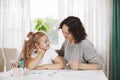 Mom helps her little daughter do her homework. Mom teaches the girl to draw. Home training, online training Royalty Free Stock Photo
