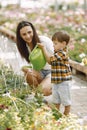 Mom helps her little son water flowers in the greenhouse