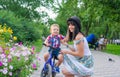 Mom helps a little boy riding a bike ride in a summer park Royalty Free Stock Photo