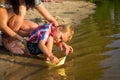 Mom helps the little boy to lower the paper boat to the water Royalty Free Stock Photo