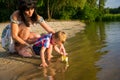 Mom helps the little boy to lower the paper boat to the water Royalty Free Stock Photo