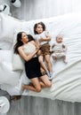Mom and her children are lying on the bed in a bright bedroom, top view Royalty Free Stock Photo