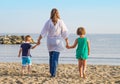 Mom and her children walk hand in hand at the beach