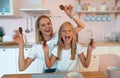 Mom with her daughter fooling around in the kitchen holding American chocolate chip cookies in her hands. dressed alike