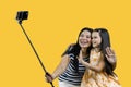 Mom and her daughter are making a common photo on smartphone using selfie stick. Royalty Free Stock Photo