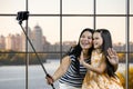 Mom and her daughter are making a common photo on smartphone using selfie stick. Royalty Free Stock Photo