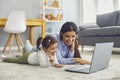 Mom with her daughter watching cartoons or entertainment video online at home. Parent and child with laptop on floor Royalty Free Stock Photo