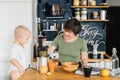 Mom and her little baby together prepare tasty juice from fresh oranges Royalty Free Stock Photo