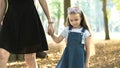 Mom and her little daughter child walking together holding hands in summer park Royalty Free Stock Photo