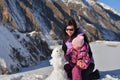 Mom and her little daughter in the winter sculpt a snowman in the mountains. Royalty Free Stock Photo