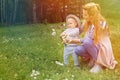 Mom and her little son love to relax and walk in a summer park on a green flower meadow