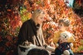 Mom and her little son are talking and having happy time on walk in the autumn park. Motherhood. Mother and baby boy