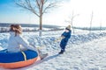 Mom with her little son 3 years old, riding Tubing on a sunny day in city in winter. Play Snorkeling. Happy Scrabing