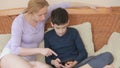 Mom and her son teenager speak well, look at the tablet touch the touch screen